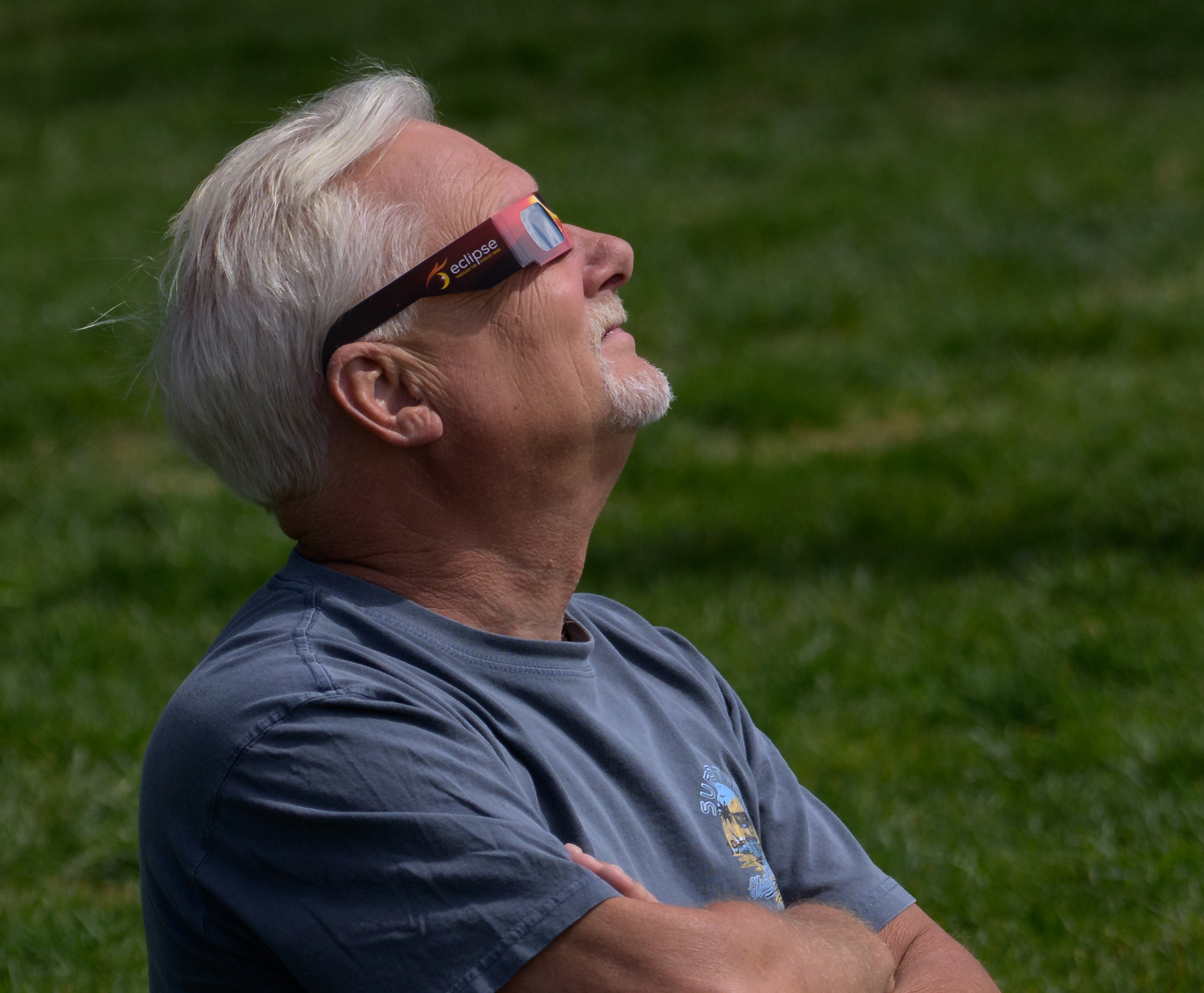 A man watching a partial solar eclipse through cardboard protective glasses